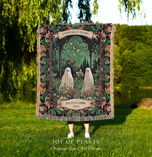 May include: A decorative throw blanket featuring a whimsical design with two ghost figures in a garden setting. The blanket has a dark border with floral and leaf patterns, and the text "Eternally Yours" and "Dylan & Gabby 2025". The blanket is fringed.