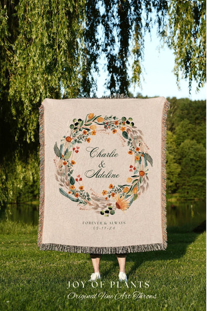 May include: Beige throw blanket with a floral wreath design. The wreath surrounds the names "Charlie & Adeline" and the date "09.17.24". The blanket has a fringed edge and the text "FOREVER & ALWAYS" is below the names.
