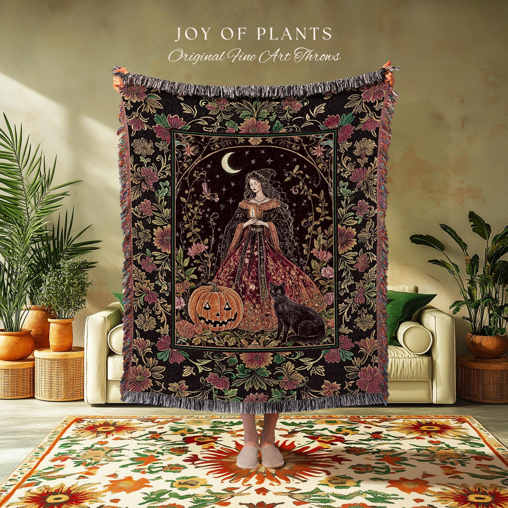 May include: A decorative throw blanket with a dark background and a central image of a woman in a gown, a jack-o'-lantern, and a black cat. The blanket has a floral border and the text "JOY OF PLANTS Original Fine Art Throws".