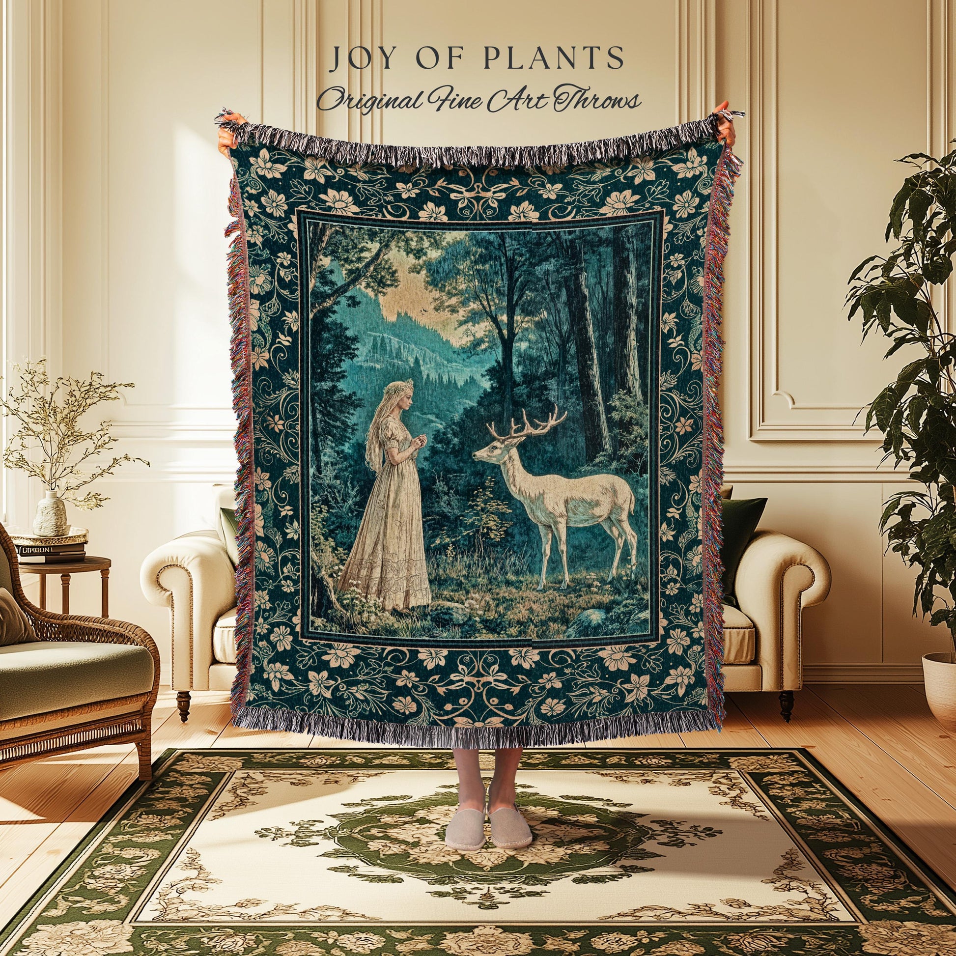 May include: A tapestry throw blanket with a forest scene featuring a woman and a deer. The blanket is dark teal with a floral border and fringe. The text "JOY OF PLANTS Original Fine Art Throws" is at the top.
