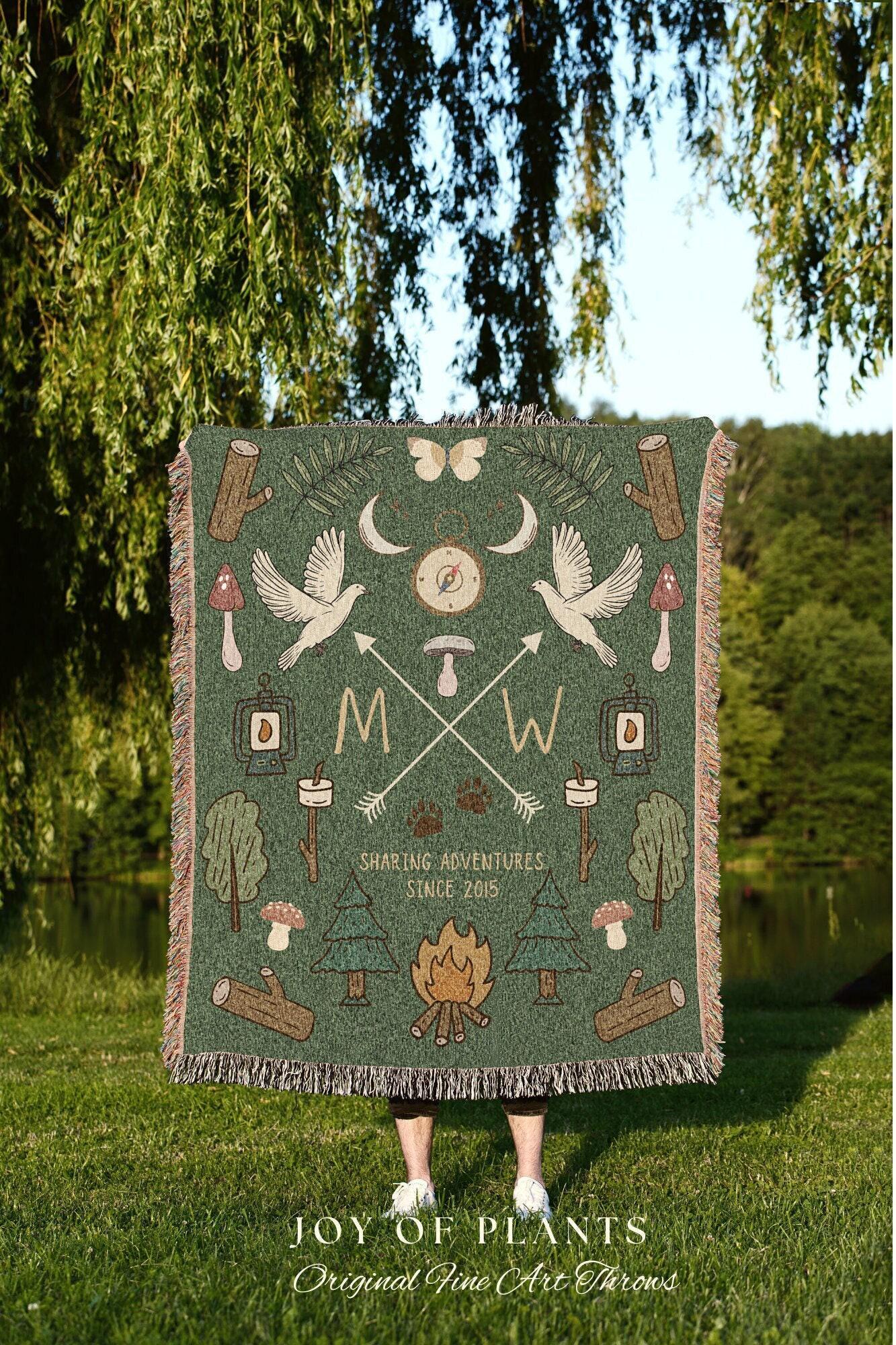 May include: Green throw blanket with a nature-themed design. Features illustrations of birds, arrows, trees, and a campfire. Text includes "Sharing Adventures Since 2015" and "Joy of Plants".