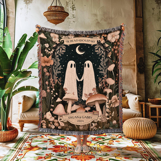 May include: A decorative tapestry featuring a whimsical design with two ghost figures holding hands under a crescent moon. The tapestry includes the text "TIL DEATH DO US PART" and the names "DYLAN & GABBY 2024". The color palette includes shades of green, brown, and cream.
