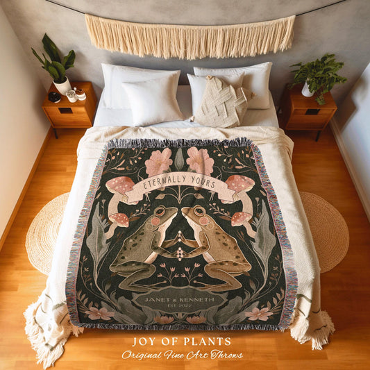 May include: A dark green throw blanket featuring a design of two frogs holding hands, with the text "Eternally Yours" above them. The blanket also includes the names "Janet & Kenneth" and the year "2022". The words "JOY OF PLANTS" and "Original Fine Art Throws" are at the bottom.