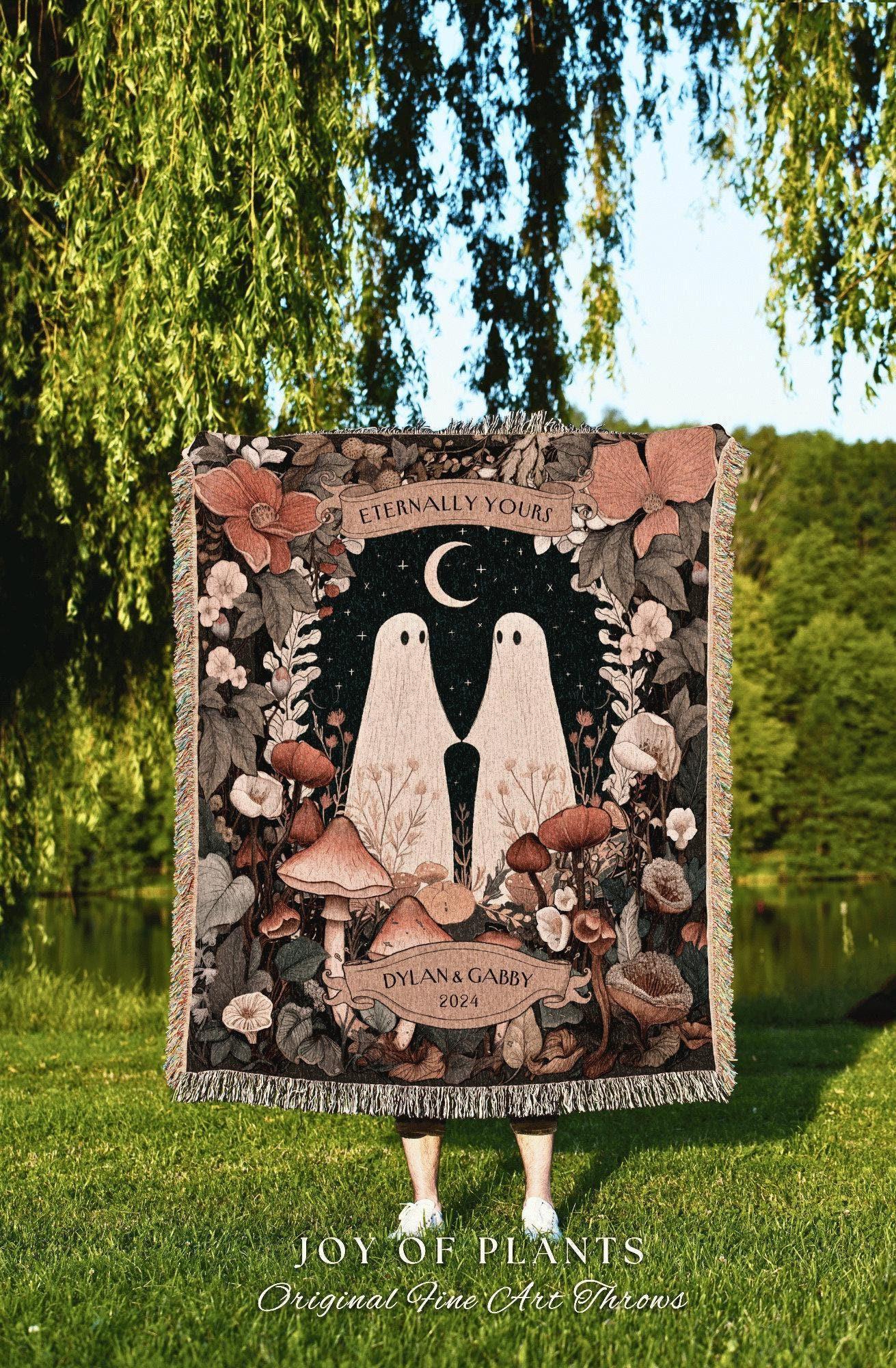 May include: A woven throw blanket featuring a whimsical design with two ghost figures under a crescent moon, surrounded by mushrooms and flowers. The words "Eternally Yours" and "Dylan & Gabby 2024" are displayed on the blanket.