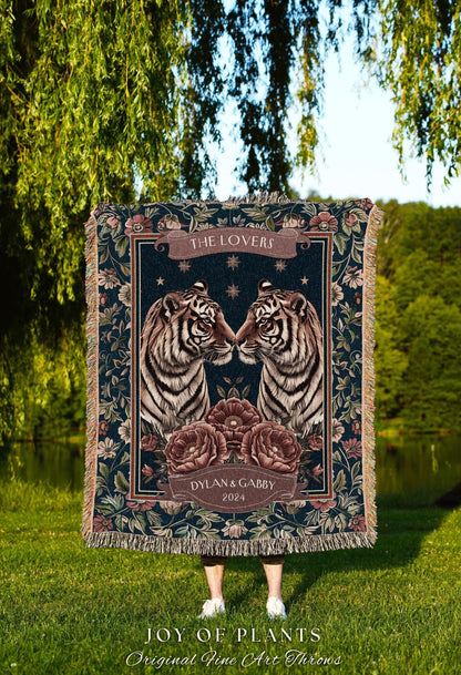 May include: A dark blue throw blanket featuring two facing tigers with floral and banner accents. The banner reads "THE LOVERS" and "DYLAN & GABBY 2024". The blanket has a fringed edge and is set against a natural background.