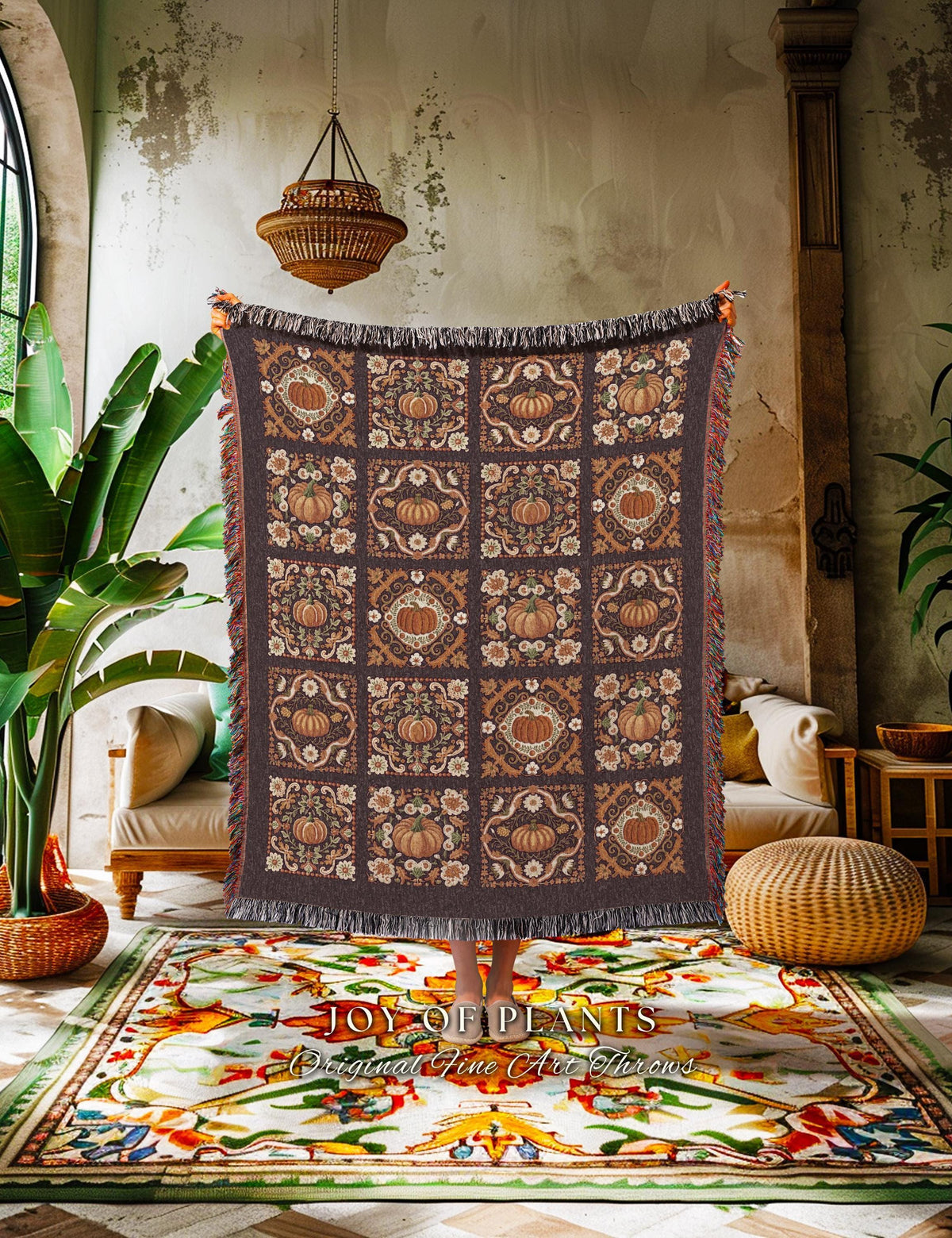 May include: A dark brown throw blanket with a repeating pattern of pumpkins and floral designs in shades of orange and cream. The blanket has a fringed edge and is displayed indoors.