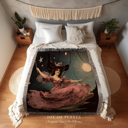 May include: A woven throw blanket featuring a vintage illustration of a woman in a pink dress and witch hat, holding a wand. The design includes stars, a moon, and the text "JOY OF PLANTS Original Fine Art Throws."