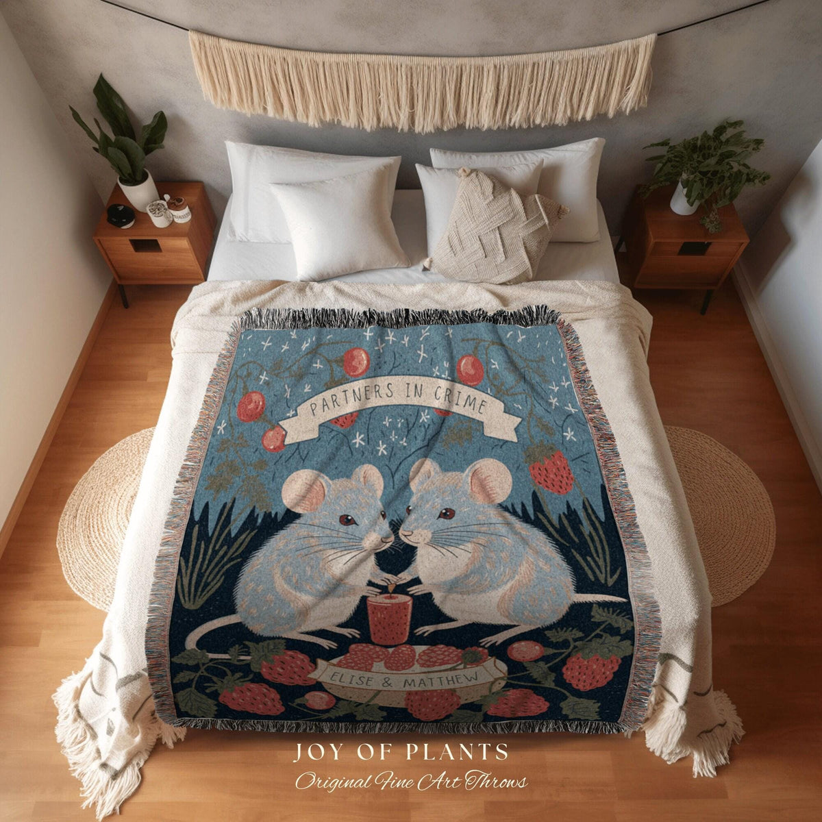 May include: A blue throw blanket with a whimsical design featuring two light blue mice holding a small jar. The blanket has the words "PARTNERS IN CRIME" on a banner and is decorated with strawberries and foliage. The text "JOY OF PLANTS" is at the bottom.
