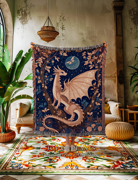 May include: A tapestry throw blanket featuring a detailed illustration of a dragon with outstretched wings, set against a starry night sky with a full moon and butterfly. The blanket has a fringed edge and is in shades of blue, brown, and beige.