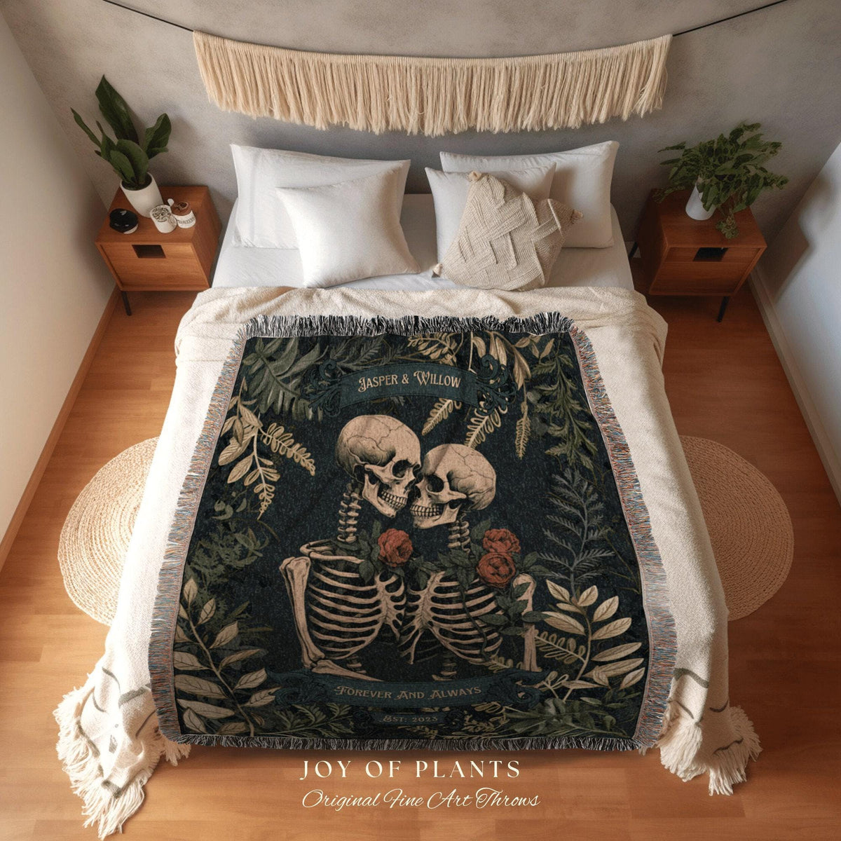 May include: A woven throw blanket featuring a design of two skeletons embracing, surrounded by foliage and roses. The blanket has a dark green background with the text "Jasper & Willow" and "Forever and Always". The blanket is fringed.